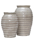 Two large beige ceramic vases with textured horizontal stripes highlight timeless elegance. One vase, the 38-429 Jaxton Short Vase by The Import Collection, is side by side with another against a plain white background.