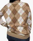 A person is seen from the back wearing the Brazeau Tricot Argyle V-Neck in camel with thin red lines, paired with dark jeans and one hand on their hip.