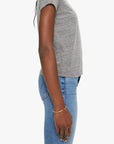 A person stands in profile against a plain background, wearing Mother’s The Lil Goodie Goodie Tee in grey. Their right arm hangs relaxed by their side, embodying the timeless ease of this essential short-sleeve crewneck.