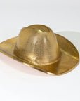 The Import Collection’s Westin Hat is a gold cowboy hat sculpture with a shiny, metallic finish, shown on a plain white background—a bold accent piece for western decor.
