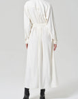 A person wearing the long-sleeved, ankle-length camillia shirt dress in portofino twill by Citizens Of Humanity/AGOLDE, belted at the waist with black heeled boots, photographed from the back against a plain light background.