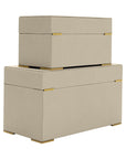 The Import Collection's Ramato Boxes feature two beige modern storage boxes, one smaller stacked on a larger one, both with gold corner accents and short legs, serving as decorative storage against a white background.