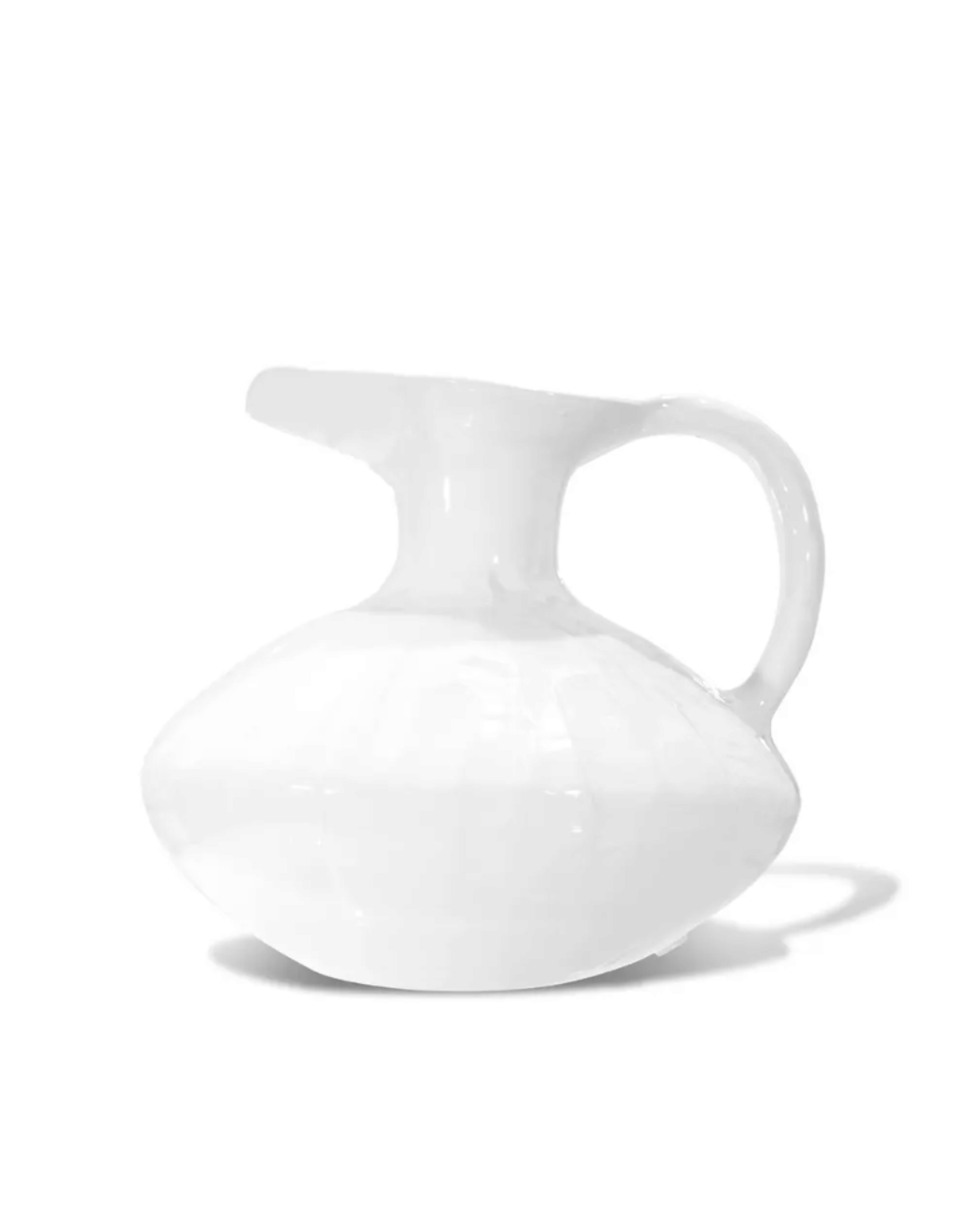A simple white ceramic Montes Doggett Pitcher No. 431 with a round body and an elegant handle, set against a plain white background in a Scottsdale, Arizona bungalow.