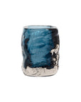 The Import Collection's Hendrick vase is a blue glass tumbler with an irregular, textured surface and metallic silver accents at the base and lower sides, displayed against a white background.