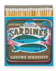 Faire’s Matches/Square features a matchbox designed by Saint No, with two illustrated sardines and bold “SARDINES” and “LUXURY MATCHES,” styled like a classic sardine tin.