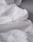 Close-up of the Antik Matelasse Coverlet by Matteo, featuring a textured white jacquard weave that forms soft folds and shadows for added depth and comfort.