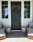 Chic porch setup with two cushioned chairs and a Birdie Pillow by Faire, accented by planters and a small rug.