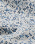 A close-up of Faire’s Blue Mini Meadow Euro Sham shows 100% cotton percale with a white background and small blue floral pattern, featuring gentle folds and shadows from the slightly wrinkled fabric.