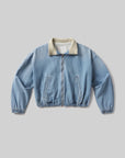 The bubble bomber in marseille by Citizens Of Humanity/AGOLDE features vintage indigo denim, a beige collar, front zipper, two slanted pockets, and elastic cuffs and waistband. Shown in light blue crosshatch denim on a plain gray background.