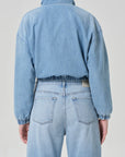 A person is shown from the back wearing the Citizens Of Humanity/AGOLDE bubble bomber in marseille, a light blue denim jacket with elastic cuffs and waistband, paired with matching high-waisted light blue vintage indigo wash jeans.