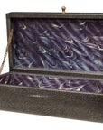 The Gatsburg Shagreen Box by Sarreid is rectangular, tawny brown, with a hinged lid topped by a gold knob. Inside, it has a purple marbled lining and a small gold chain securing the open lid.