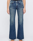 Only the lower torso and legs are visible as a person stands against a plain white background, wearing Moussy's Lismore 70's Flare high-waisted blue jeans paired with black pointed-toe shoes.