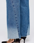 A close-up of a person wearing Moussy's Holyoke Panel Wide mid-rise, wide-leg faded blue jeans with frayed hems and black pointed-toe kitten heels against a light, plain background.