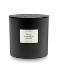 A 55 OZ black cylindrical coconut wax candle by Faire, featuring a wooden lid and a label reading "ENVIRONMINT ALCHEMY, BAIES CURRANTS QUINCE, AROMATIC CANDLE" in black text—a diptyque-inspired accent for refined spaces.
