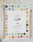 Spiral-bound Celebrate watercolor workbook with cake cover and colorful art accents by Faire.