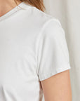 A close-up of a person wearing the Perfectwhitetee Springsteen Baby Tee, a plain white short-sleeve shirt, highlighting the shoulder, sleeve, and part of the neck against a light background.