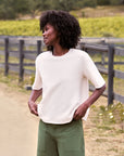 Green pants styled with a Frank & Eileen Perry NYC Crew Tee, worn casually outdoors by a wooden fence.