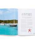 An open issue of Sailing The Seas V2 by Ingram Book Company shows sailboats in turquoise waters with green hills beyond, evoking top sailing destinations. The opposite page has text and a red starfish illustration.
