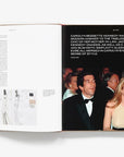 An open book, "CBK: Carolyn Bessette" by Hachette Book Group, shows a fashion sketch and a photo of a couple in formal wear at an event, with text highlighting Carolyn Bessette Kennedy's enduring style as a fashion icon.