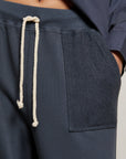 A close-up of a person wearing the Perfectwhitetee French Terry Pant—navy blue, 100% cotton, straight-leg lounge pants with a textured patch pocket and white drawstring—paired with a matching navy top.