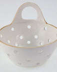 The Yara Colander Basket by Be Home is a handcrafted stoneware bowl with a handle and multiple round holes, skillfully made by women artisans and photographed against a plain white background.