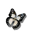 The Faire Fashion Hair Clip is a black and white butterfly design with white spots, made from eco-friendly cellulose acetate and shown on a white background with shadow.
