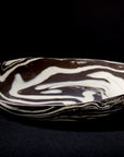The Faire Porcelain Serving Bowl - Black & White 10" boasts a handcrafted marbled design with swirling black and white patterns, perfect for stylish serving.