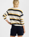 Seen from behind against a plain light background, a person with blonde hair in a low bun wears the One Grey Day Susannah Pullover—a striped sweater—paired with dark navy shorts.