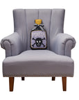 Faire Poison Bottle Hook Pillow by Bungalow Furniture, with a quirky Halloween design on a gray armchair.