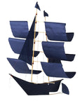 A model sailboat with a black hull and three masts, each with dark blue sails and small flags, resembles the Faire Sailing Ship Kite, set against a plain white background.