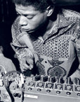 In a black and white photo echoing Basquiat’s creative energy, a young man in a patterned shirt adjusts sound mixer controls—a scene inspired by "Seeing Loud, Basquiat and Music" from Simon & Schuster Inc.