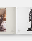 An open copy of "Way of Living: Art of Willem de Kooning" by Hachette Book Group displays one page with an artist sculpting in a studio, and the other with a finished abstract humanoid sculpture reflecting Abstract Expressionism.