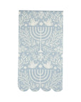 The MME Napkin by Faire is adorned with a light blue and white symmetrical design, showcasing doves, menorahs, floral patterns, and stars. It also features scalloped edges.
