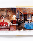 An open copy of "Slim Aarons: Women" by Hachette Book Group displays photos of extraordinary women in glamorous ball gowns—one in red on the left, one in blue on the right—channeling iconic high-society style.