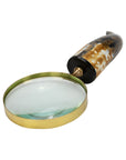 The Import Collection’s Abbott Magnifying Glass features a brass frame and a brown, black, and white marbled handle, making it a stylish decorative accent. Photographed on a white background.