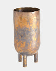 The Alchemy Container Burnt Brass T by Global Views is a tall, cylindrical metallic vase with a mottled gold and bronze oxidized brass finish, wavy rim, and three short rounded legs, shown against a plain light background.