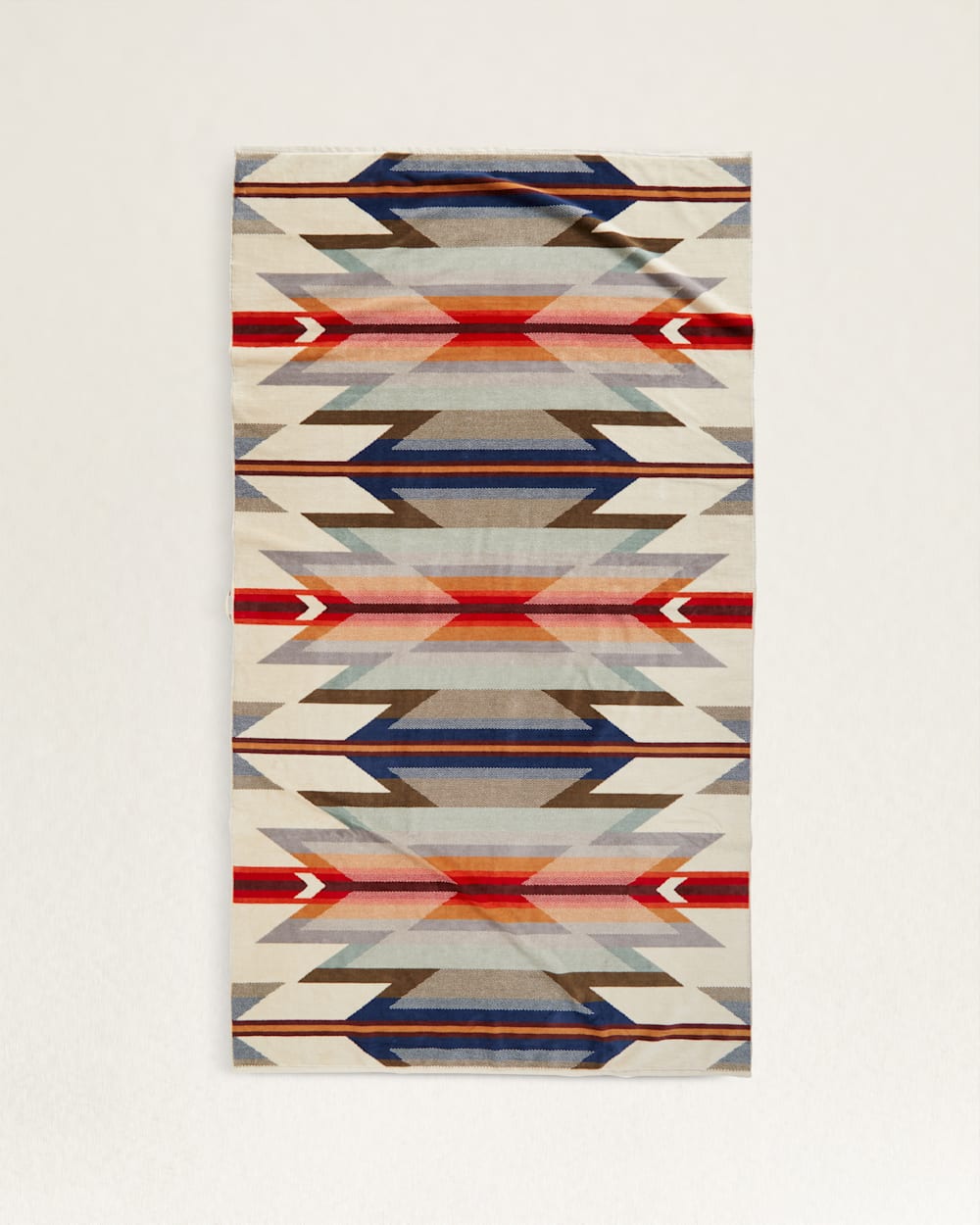 A colorful rectangular rug with a geometric pattern featuring angular shapes in shades of blue, red, beige, and gray on a cream background, perfect for a bungalow in Scottsdale, Arizona. - Pendleton/Babblitt's Wholesale spa towel