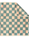 A green and peach square waffle weave microfiber washcloth with a checkerboard pattern, one corner folded over. A white fabric label with the brand name "Faire" is stitched on the edge.