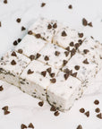 Nine square Faire Choc Chip Marshmallows, studded with chocolate chips and arranged on white marble with extra chips scattered around, make a delicious dairy-free, allergy-friendly treat.