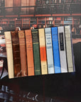 Colorful vintage books upright on a glass tray, styled for Bungalow Furniture & Accessories library decor.