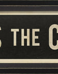 The Street Sign In Black by Spicher And Company features bold white uppercase lettering reading "KISS THE COOK" on a vintage-style black background with a thin white border—a perfect framed sign for lovers of unique vintage wall decor.