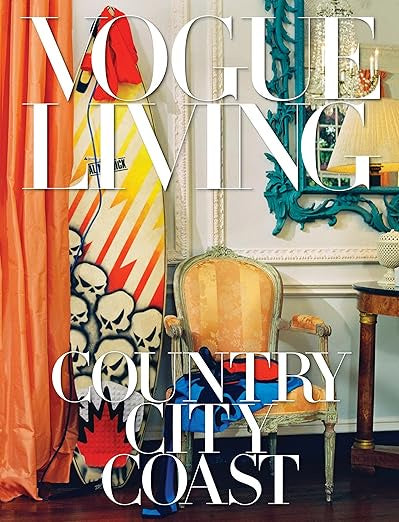 A stylish interior scene features a vintage armchair, a colorful surfboard decorated with skull designs, and a lamp resting on a side table. The magazine cover promotes "Vogue Living: Country, City, Coast" from Random House, providing inspiration from exclusive Vogue homes.