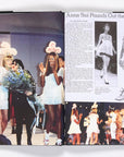 A fashion magazine spread shows models in white baby-doll dresses with angel wings on the runway. The right page features an article about Nineties X Anna Sui by Random House, highlighting ’90s-inspired fashion and runway photos.