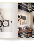 The Ingram Book Company’s "Creating A New Home In Mallorca" shows a close-up of vintage electrical outlets and a grand hallway with checkered floors, arches, and decor inspired by a Mallorca home renovation across two illustrated pages.