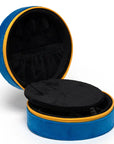 The Caviar Jewelry Case is round and blue with yellow trim, featuring a velvet exterior. It opens to reveal a black interior with compartments and an elastic pocket inside the lid.