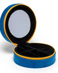 The Caviar Jewelry Case is a round blue velvet organizer with a yellow zipper, featuring a mirror in the lid and black divided compartments—perfect as a stylish jewelry box or a compact travel case.