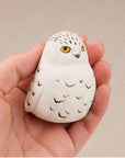 Faire white hand-carved songbird figurine held in hand, perfect for nature-inspired home decor.