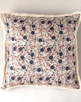 The Block Print Pillow by Faire features a detailed botanical print of dark blue berries and red branches on a cream background with off-white fringe trim. This vintage throw pillow is shown against a plain light surface.