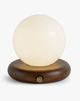The Valencia Portable Light by Faire features a round frosted glass shade atop an oval wooden base with a metal knob, set against a plain white background.