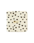 The MME Cocktail Napkin by Faire features a simple and elegant design with black heart patterns on a white scalloped edge. A small gold label with text adorns the center.
